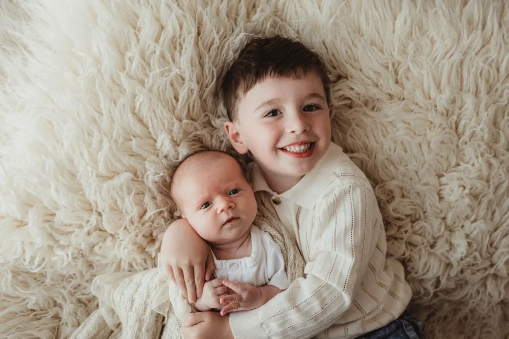 big sibling holding swaddled newborn bub photography